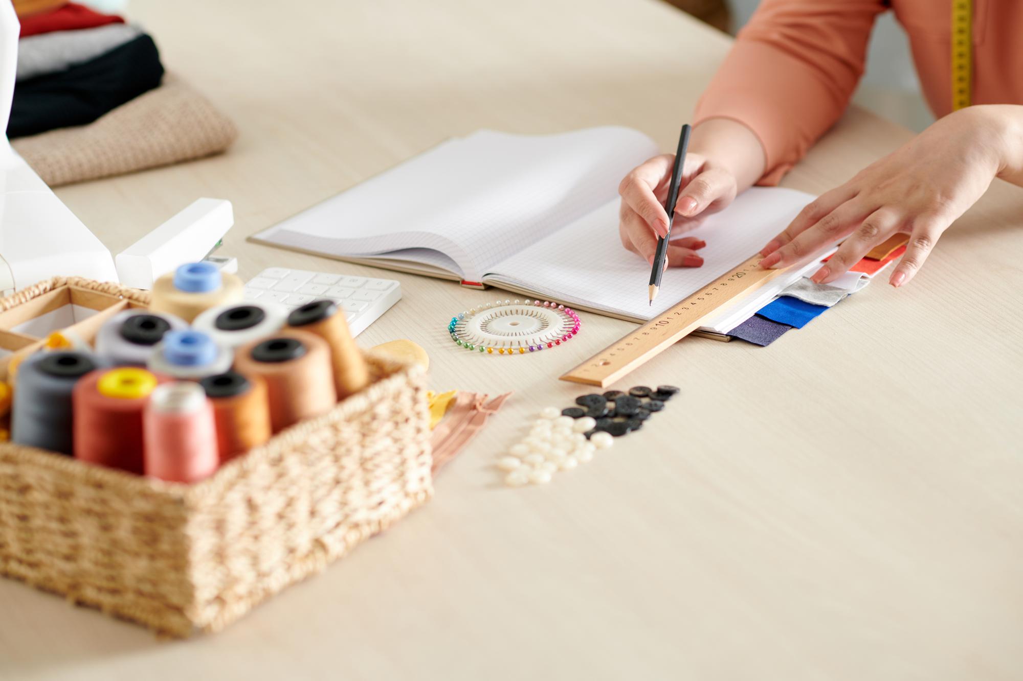 Artisan arranging threads and sketches on a wooden table